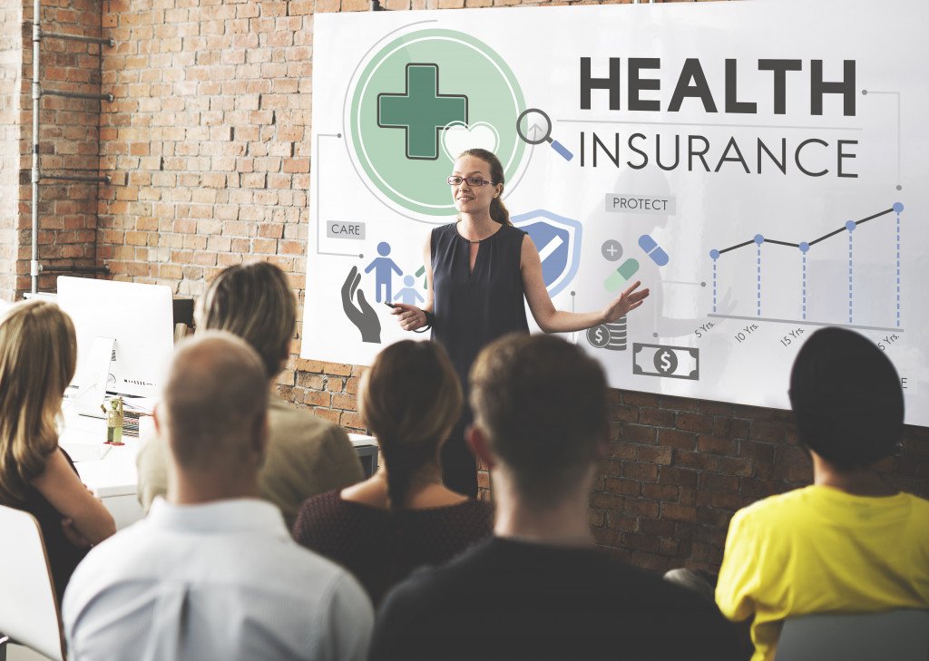 woman explaining health insurance in front of employees